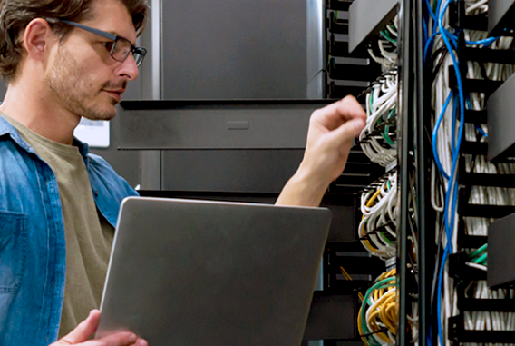 Worker With Glasses Setting Up IT Infrastructure and Cabling With Laptop​​