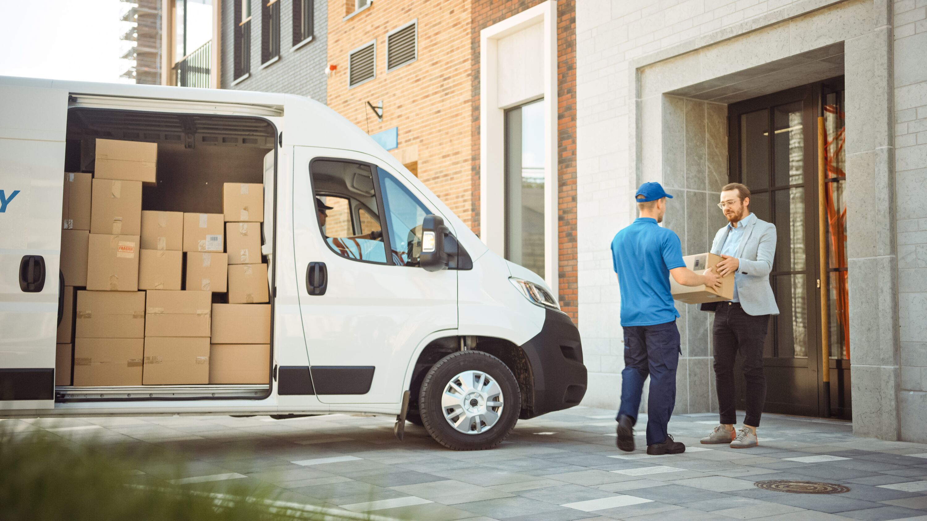 Man handing a package to a customer with a full delivery truck